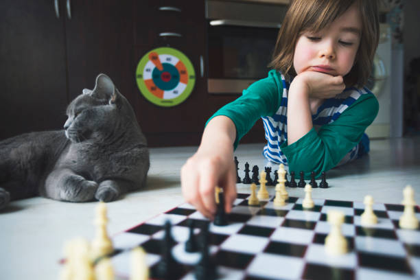 istock Little boy playing chess. Cat next to him. 1217687404