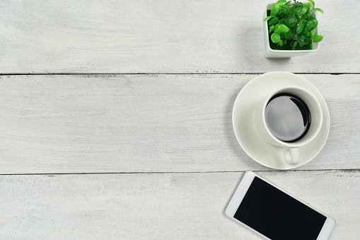 Coffee and smartphone on white wooden table background. office supplies concept. top view. copy space.