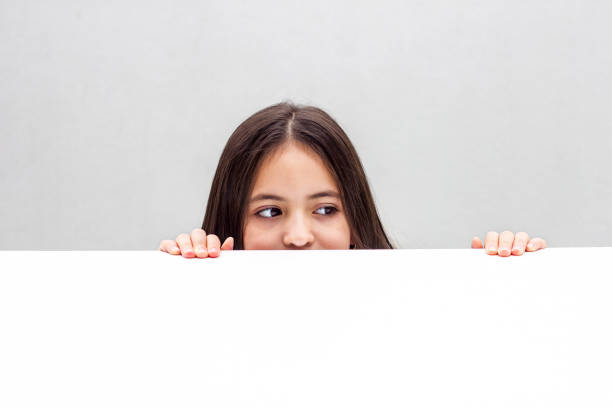 Girl looks out from behind the table. isolated on white background Girl looks out from behind the table. isolated on white background animal finger stock pictures, royalty-free photos & images