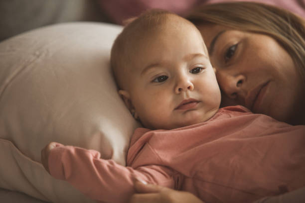 istock Cute baby girl lying down  with mom hugging her 1217691725