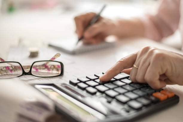 istock Pension calculation concept, old hands counting finances on a home calculator , close- up 1217692524