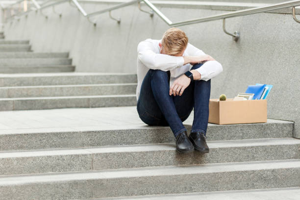 perdre son emploi, le jeune homme a perdu son emploi, assis sur des escaliers tenant la tête baissée, déprimé, pleurant et ne savent pas quoi faire en temps de crise. - lost in time photos et images de collection