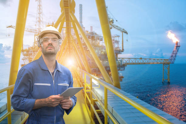 istock Caucasian man engineer staff worker with tablet in hand and offshore rig background concept. 1217694147