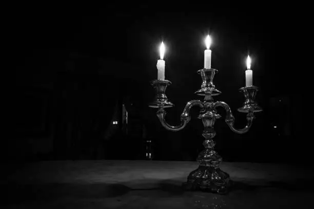 Old silver chandelier with three lit candles.