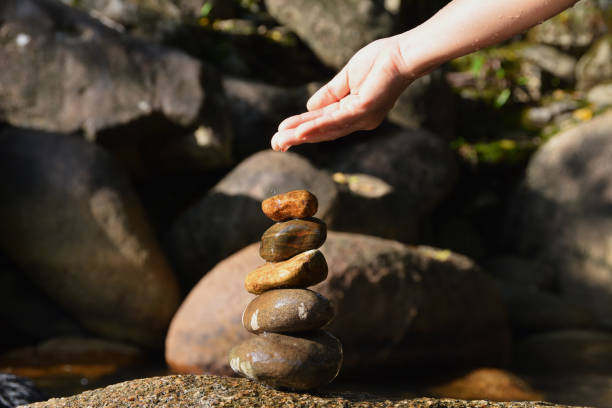 istock Stack of zen stones with hand on waterfall background 1217709620