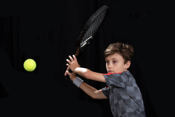 istock Boy playing tennis on black background 1217710737