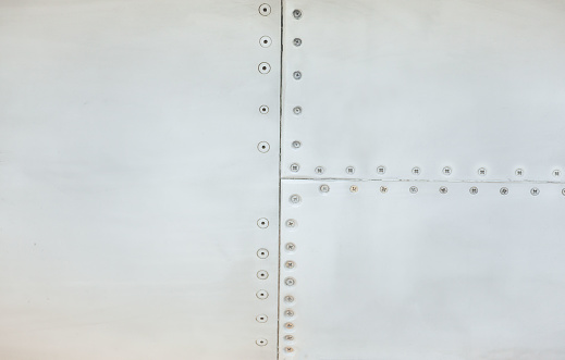 Silver metal surface of the aircraft fuselage with rivets. Fuselage detail view. Airplane metallic fuselage detail with rivets.