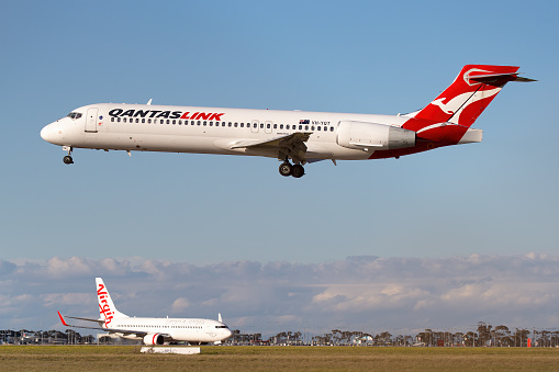 Melbourne, Australia - June 23, 2015: Boeing 717 regional airliner operated by QantasLink on approach to land at Melbourne Airport with a Virgin Boeing 737 taxiing in the background.