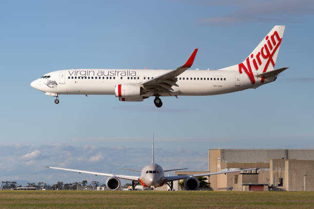 el boeing 737-800 de virgin australia airlines está a punto de aterrizar en el aeropuerto de melbourne mientras un boeing 787 de jetstar airways espera para partir. - depart fotografías e imágenes de stock