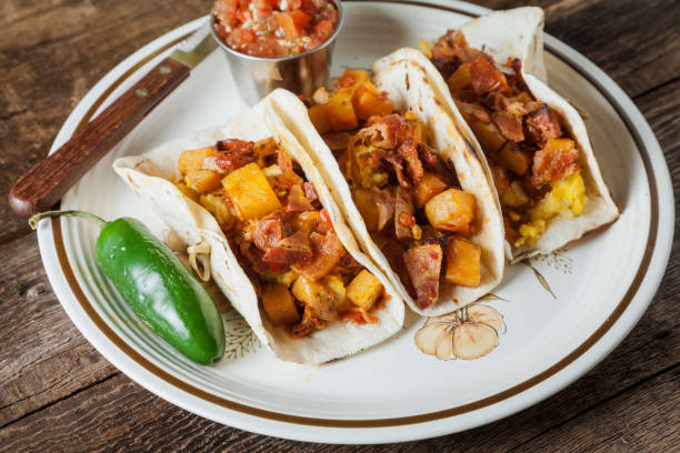 Tacos filled with migas, a Tex-Mex dish of eggs scrambled with red bell pepper, onions, jalapenos, cheese, topped with avocado, cilantro, cherry tomatoes