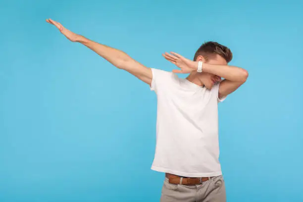 Photo of Portrait of excited happy man in white t-shirt showing dab dance, popular internet meme pose