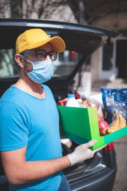 Delivery guy with protective mask and gloves delovering groceries during lockdown and pandemic. Delivery guy with protective mask and gloves delovering groceries during lockdown and pandemic. home delivery photos stock pictures, royalty-free photos & images