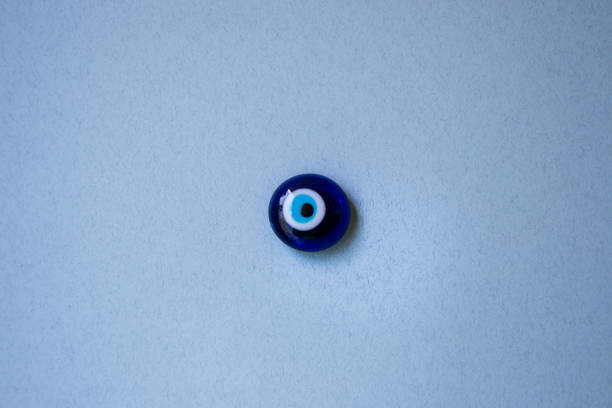 стеклянный турецкий глаз "nazar boncugu" на бледном фоне, объект, суеверие концепции, в помещении - nazar boncugu стоковые фото и изображения