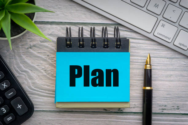 istock PLAN text with decorative flower, calculator, fountain pen, keyboard and notepad on wooden background 1217732458