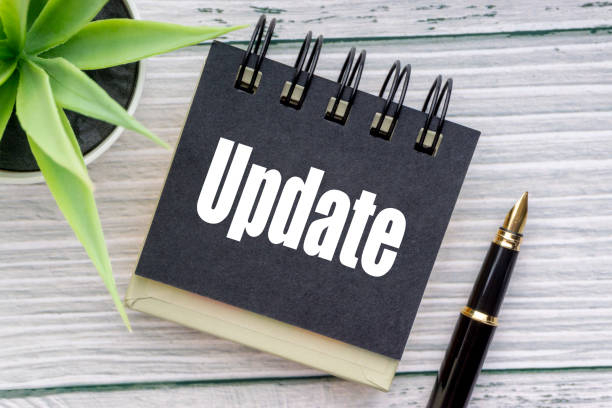 UPDATE text with decorative flower, fountain pen and notepad on wooden background