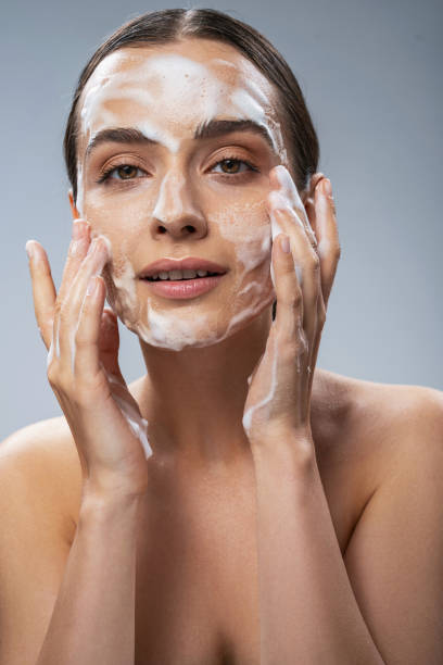 istock Cheerful young female washing her face with soap 1217732935