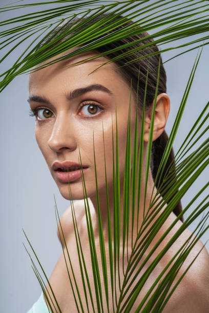 istock Young pretty woman behind exotic green plants 1217732975