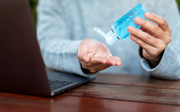 istock a woman using and applying alcohol gel to clean hands while working on laptop at home for Healthcare and Covid-19 or 2020 virus concept 1217733187