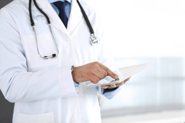 istock Doctor man using tablet computer for network research or virtual disease treatment, hands close-up. Perfect medical service in clinic. Modern medicine, medic data and healthcare concepts. Toned picture 1217735728
