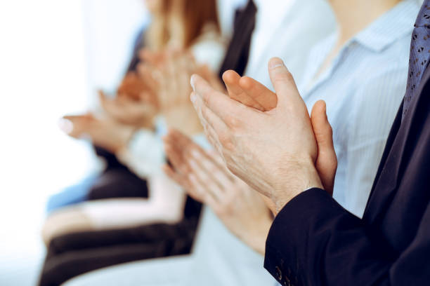 Business people clapping and applause at meeting or conference, close-up of hands. Group of unknown businessmen and women in modern white office. Success teamwork or corporate coaching concept. gente de negocios aplaudiendo y aplaudiendo en la reunión o conferencia, primer plano de las manos. grupo de hombres de negocios y mujeres desconocidos en la oficina blanca moderna. trabajo en equipo de éxito o concepto de coaching corporativo