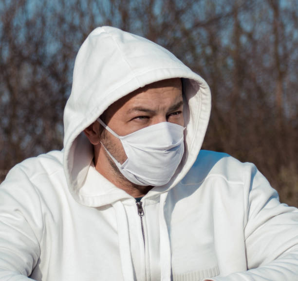 istock Man dressed in white, with hood on head and protective mask. 1217738361