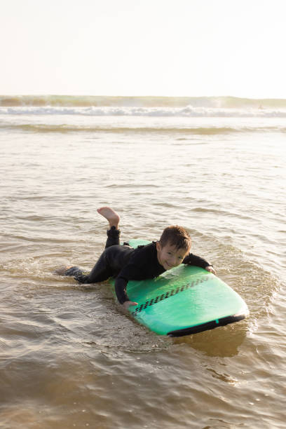 istock Cute little boy floating on green surfboard 1217742165