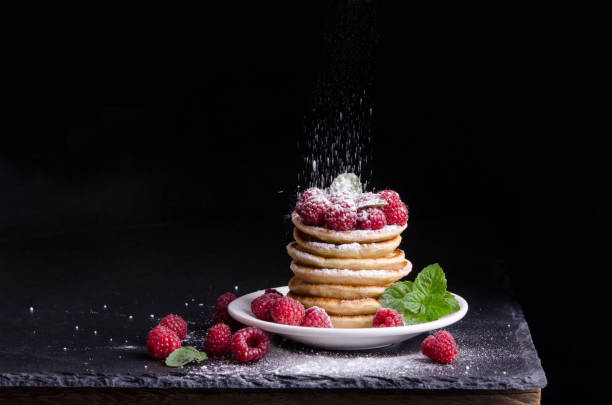 istock Pancakes with raspberries around on black backgound 1217745495