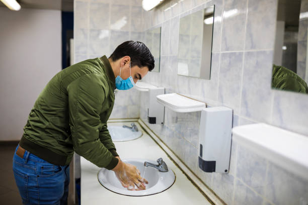 istock Man washing his hands to avoid diseases like coronavirus Man with a face mask washes his hands in a public bathroom 1217746793
