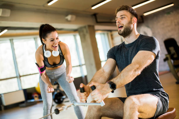 istock Young man using seated row machine in the gym with support of female coach 1217746852