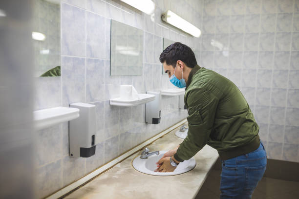 istock Man washing his hands to avoid diseases like coronavirus Man with a face mask washes his hands in a public bathroom 1217746861