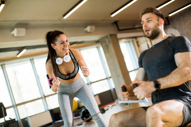 istock Young man using seated row machine in the gym with support of female coach 1217746884