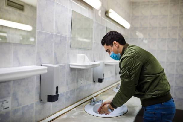 istock Man washing his hands to avoid diseases like coronavirus Man with a face mask washes his hands in a public bathroom 1217746979