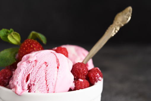 Raspberry ice cream in a bowl on a concrete background. Horizontal focus.