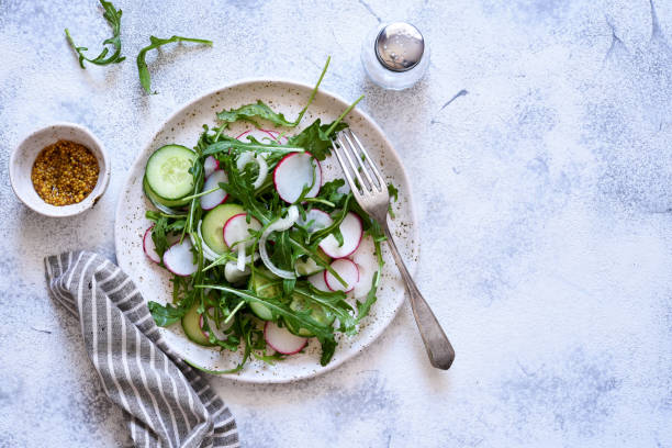 istock Vegetable salad with arugula radishes and cucumber on a concrete background 1217747396