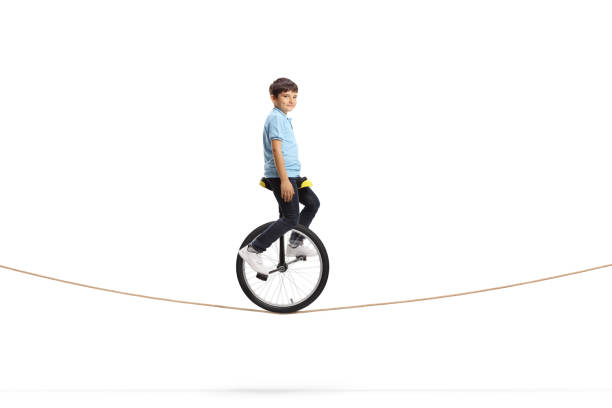 ロープに乗ってカメラを見ている少年 - unicycle unicycling cycling wheel ストックフォトと画像