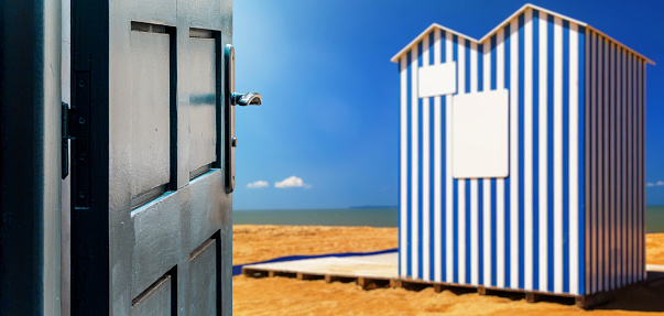 Opened door concept with a beach cabin typical of Normandy beaches on blurred background