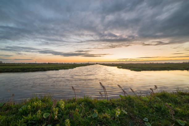 Clouds at sunset over the dutch polder landscape near Gouda, Holland Picturesque view over the wide open landscape in the west of the Netherlands. In this area you can find many green meadows intersected with channels. gouda south holland stock pictures, royalty-free photos & images