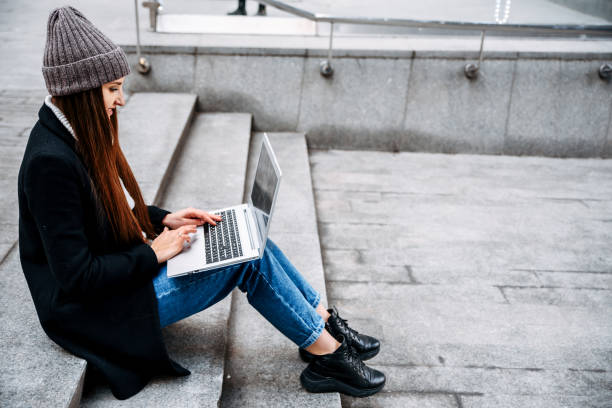 istock Woman with a laptop works sitting on a steps 1217755270