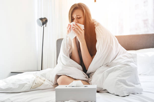 istock Sick girl sitting crossed-legged on the bed 1217759411