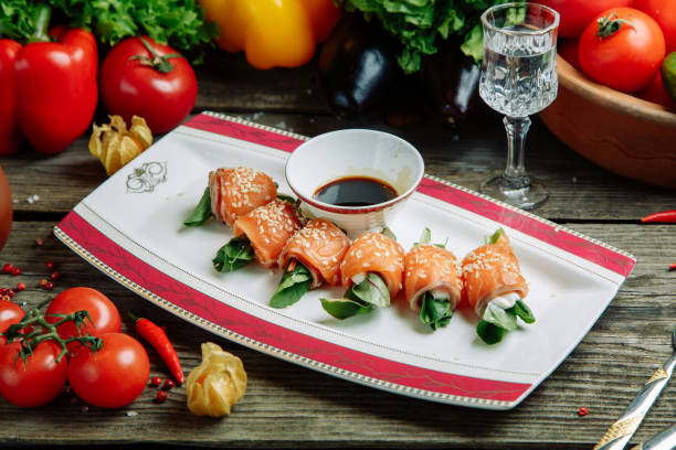 istock Roll with salmon and greens on a plate. Restaurant dish with vegetable decor on a wooden background. 1217761885