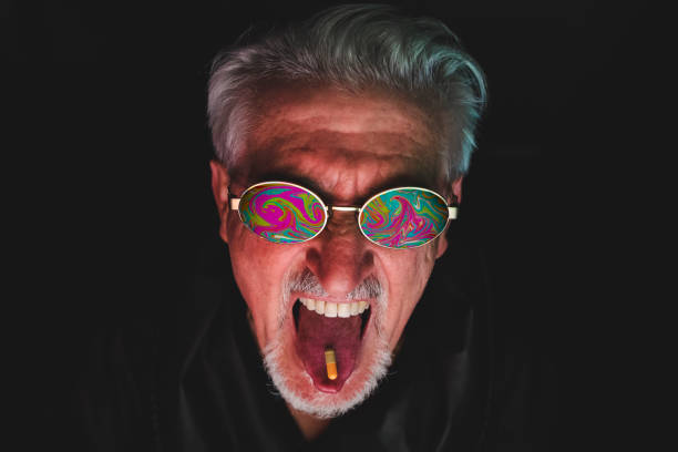 portrait of mature man in front of computer monitor is taking a medicine pill. The screen image reflected in the sunglasses