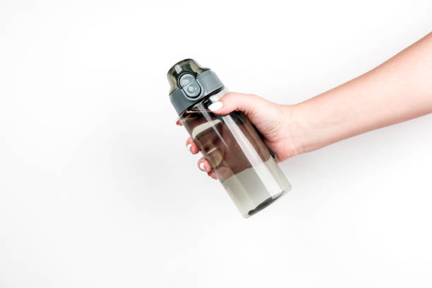 istock Sports water bottle in a woman's hand on a light background 1217765792