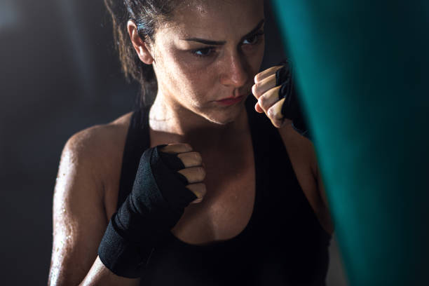 istock Female boxer punching a boxing bag in warehouse. 1217767201