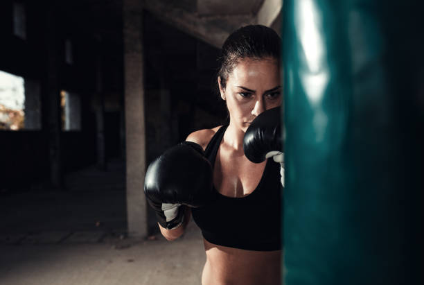 istock Female boxer punching a boxing bag in warehouse. 1217767414