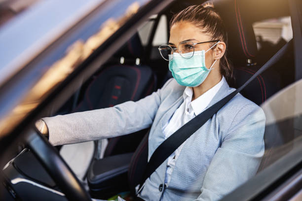 young woman with protective mask and gloves driving a car. infection prevention and control of epidemic. world pandemic. stay safe. - illness mask pollution car imagens e fotografias de stock