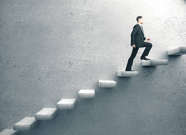 istock Businessman in suit climbing on concrete ladder. 1217770229