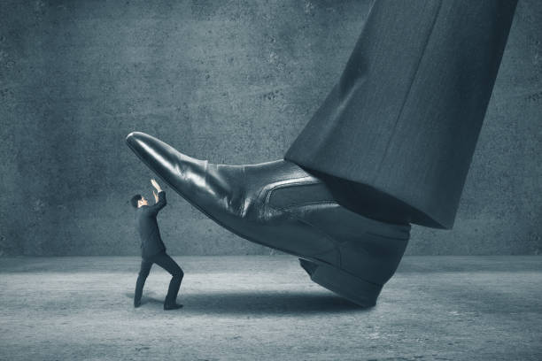 istock Big foot stepping on businessman 1217771640