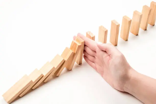 Hand stops falling wooden blocks. Crisis inhibition concept