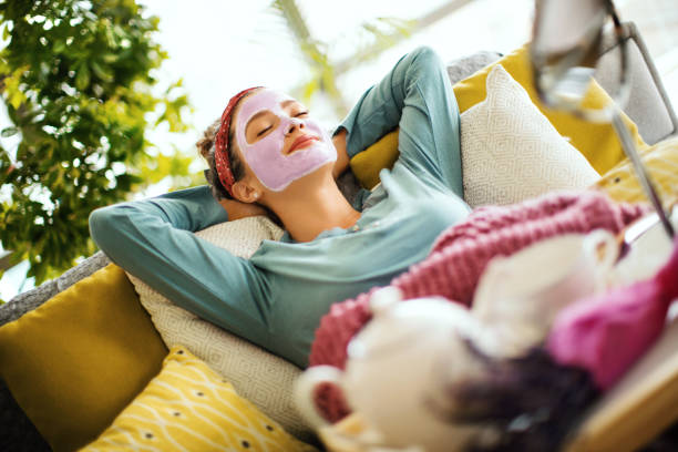 Enjoying my little spa time at home. Young woman in pajamas and with her eyes closed lying on the bed with a face mask on her face. She's enjoying every minute of it. relaxation lying on back women enjoyment stock pictures, royalty-free photos & images