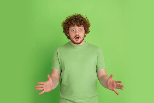 istock Caucasian young man's monochrome portrait on green studio background 1217779376